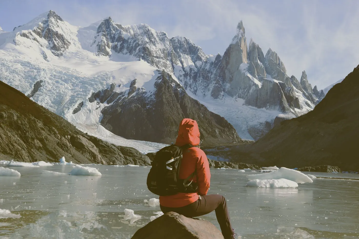 Caminante sentada frente a una laguna con témpanos